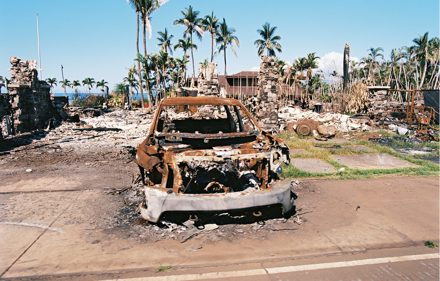 Maui fires in Lahaina aftermath featuring a burnt lot on the waterfront side of Front Street awaits debris removal